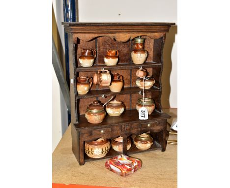 A MINIATURE WOODEN DRESSER by D.E Arthur displaying an assortment of miniature Doulton Lambeth Harvest Ware pots, tankards, f