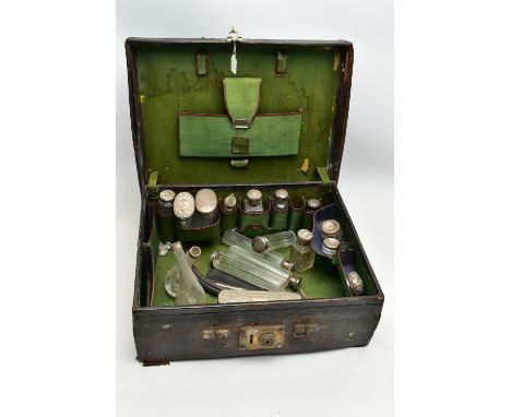 A WORN TRAVEL VANITY CASE WITH VANITY PIECES, brown leather case with metal lock fittings, opens to reveal a green fabric int