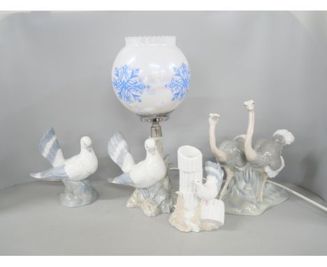 A Nao porcelain figure depicting two ostriches. three other Porceval bird figures, and a table lamp the shade a/f.