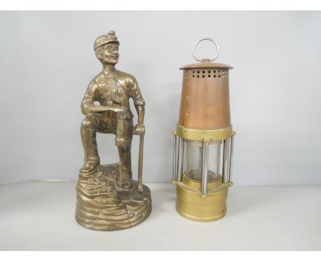 A brass miner figure and miner's lamp 