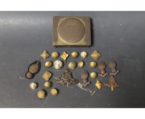 A TURTLE TYPE TIN HELMET AND A SMALL QUANTITY OF MILITARY BUTTONS AND BADGES IN A TIN