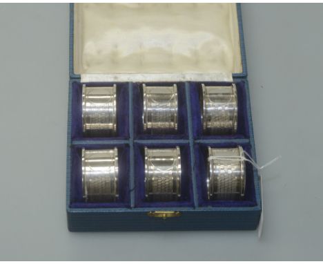 A cased set of six George V silver napkin rings, Birmingham 1912, each with engine turned decoration and vacant cartouche, 4.