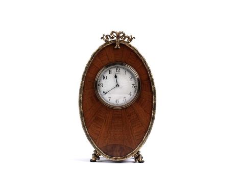 An early 20th Century walnut mantel clock, the oval solid walnut case with gilt metal mount and feet, with French 9-day movem