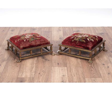A pair of Victorian brass foot stools, with reeded decoration throughout raised on paw feet, the foot pad upholstered in a re