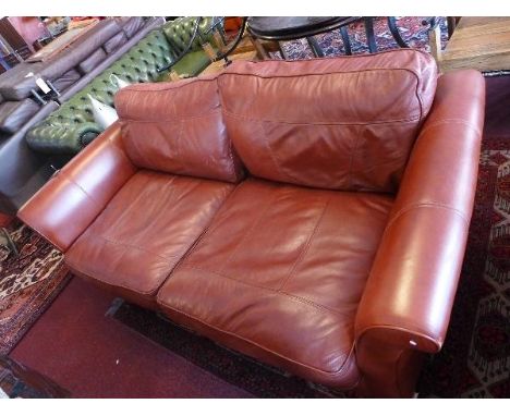 A contemporary burgundy leather three seater sofa, raised on block feet 