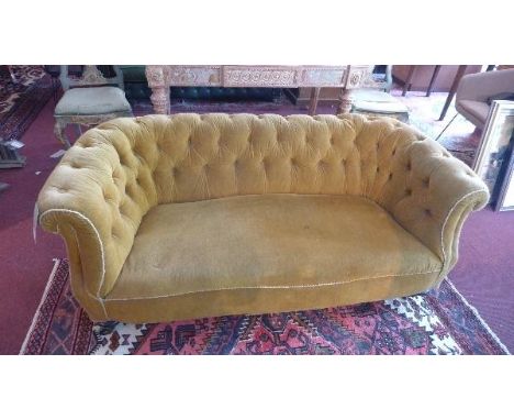 A Victorian Chesterfield sofa, with golden velour button back upholstery, raised on turned legs and castors 