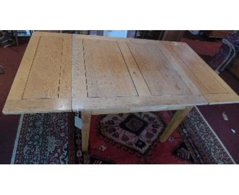 A 20th century French light oak draw leaf dining table, raised on tapered legs 