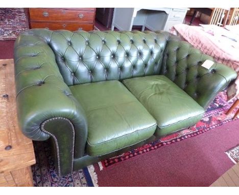 A chesterfield sofa, with green leather button back upholstery, raised on bun feet 