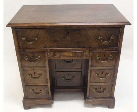A GEORGE III STYLE MAHOGANY KNEEHOLE DESK with deep drawer above a shallow drawer and flanked by two pairs of three drawers, 