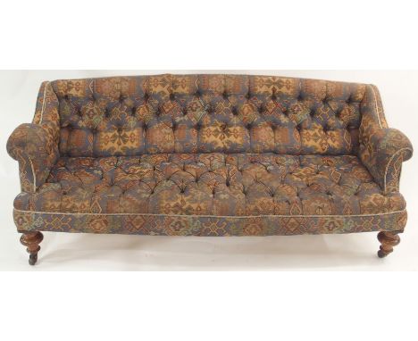 A VICTORIAN UPHOLSTERED BUTTON BACK SETTEE with walnut front ring turned legs and splayed back legs, on castors, 68cm high, 1