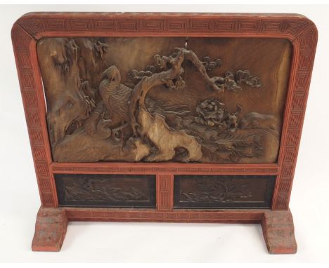 A CHINESE RED LACQUERED AND CARVED FIRESCREEN decorated in high relief with peacock and hen amongst, pine, bamboo and peonies