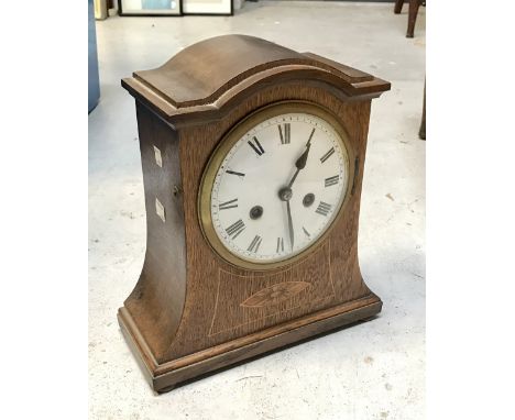 An early 20th century eight-day oak inlaid domed-top mantel clock, enamel dial set with Roman numerals, height 30cm.