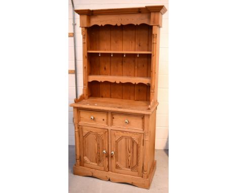 A small pine dresser with plate rack over cabinet with two short drawers and pair of cupboard doors with ceramic handles, wid