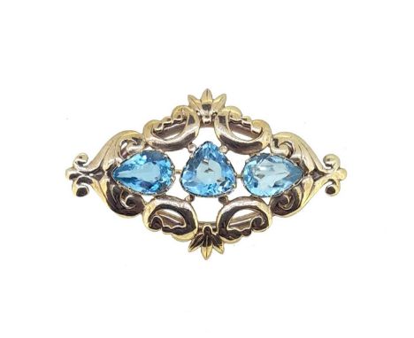 pierced scroll and foliate brooch set with a central triangular faceted aquamarine, approximately 9.8 x 9.7mm, flanked by two