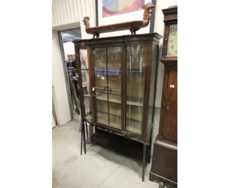 An Edwardian display cabinet with a single glazed door, with two serpentine windows and single shelf below  