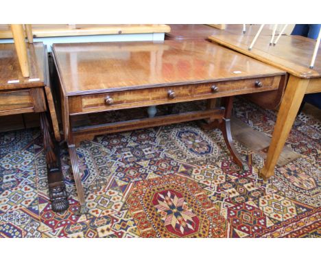 A Regency mahogany sofa table standing on reeded outswept legs with lion paw castors