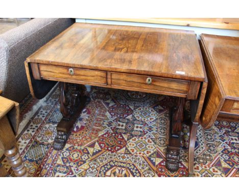 A George IV rosewood sofa table with carved shaped end supports on bold carved paw feet and inset castors