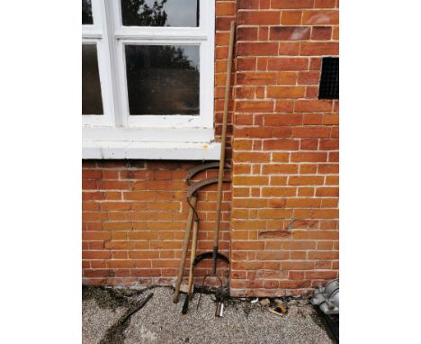 A vintage pitch fork and three vintage scythes of various sizes