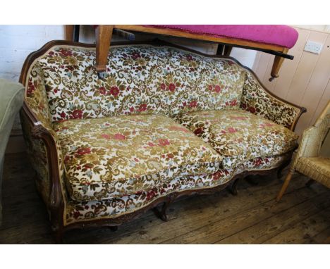 A late 19th Century four seater settee, with walnut frame with carved cabriole arms, supported on four carved cabriole legs