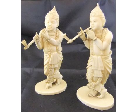 A pair of 19th Century Japanese carved ivory okimono as pipe smokers with floral garlands, raised on oval bases, 13.2 cm high