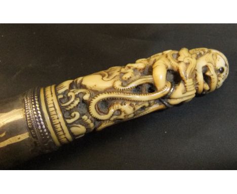 An 18th or early 19th Century Burmese Dha dagger, the silver sheathed scabbard enclosing a plain blade, the handle intricatel