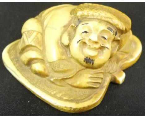 A Japanese carved ivory netsuke as a man lying upon a leaf, signed to base, 4.6cm long