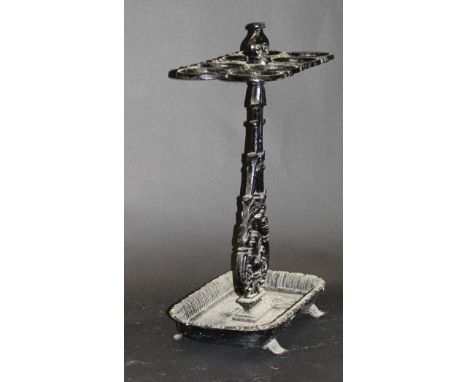 A black painted iron Victorian umbrella stick stand with scrolled handle, four figure 8 recepticles to a single pedestal of f