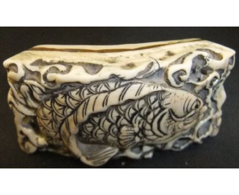 A Japanese carved elephant tooth ivory netsuke as a fish amongst rocks, of curved section, 5.4cm long
