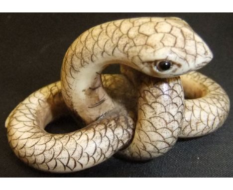 A Japanese carved ivory netsuke as a coiled snake, set with glass eyes, bears signature to base, 5.4cm long