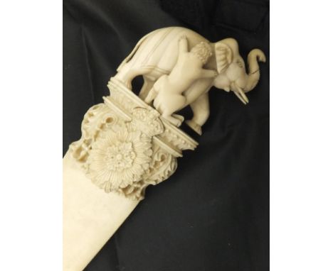 A circa 1900 carved ivory page turner of large proportions, the finial set with elephant being attacked by a lion surmount, o