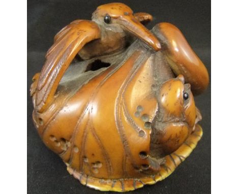 A Japanese carved ivory netsuke as a kingfisher on a leaf, with small bird beneath, carved in nut and ivory and set with glas