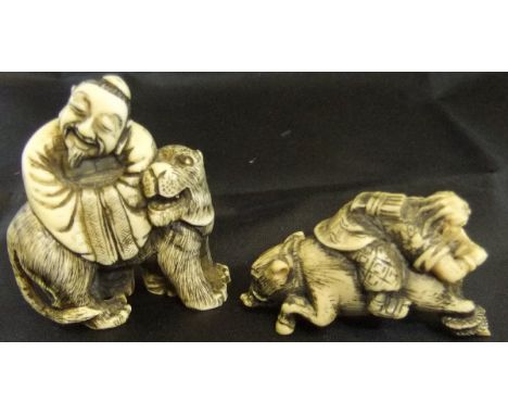 A Japanese carved ivory netsuke as a man seated reverse upon the back of a rampaging wild boar, bears signature to base, toge