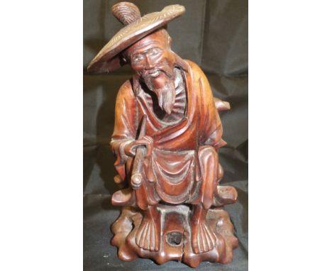 A Chinese carved treen ware figure of a pipe smoker in sunhat, seated with basket, 19 cm high