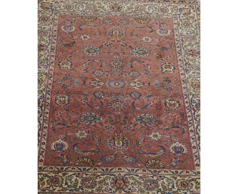 A Persian rug, the central terracotta ground with scrolling floral and foliate decoration in blue, cream, cinnamon and amber,