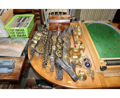 A collection of horse brasses, some on leather straps; a ladle and a brass mounted dome topped stationary box