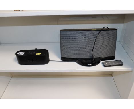 A Bose docking station with remote control and a Harman Kardon speaker
