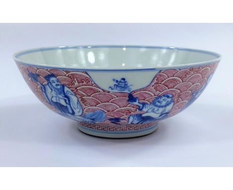 A Chinese ceramic bowl with blue and white figures of sages etc, with detailed red wave decoration to the exterior and interi