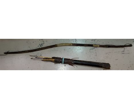 A tribal bow and arrow set, with animal hide quiver with arrows, bow bound with string. 