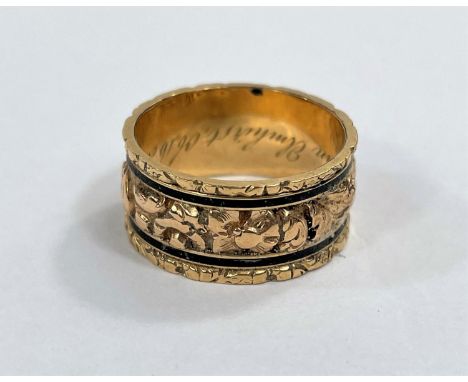 A Victorian wide mourning ring with embossed floral centre and black enamel line to each border, with internal inscription da