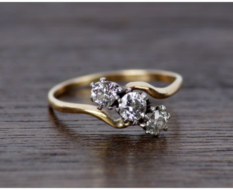 An unmarked white and yellow metal three stone diamond ring. 2.0g size J