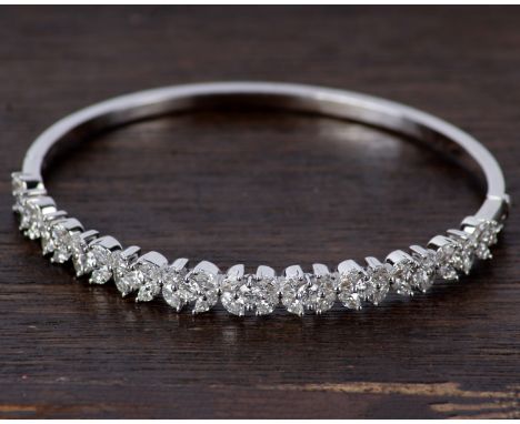 An 18k white gold and diamond set bangle. Half set with marquise and round cut diamonds of uniform clarity and cut. Estimated