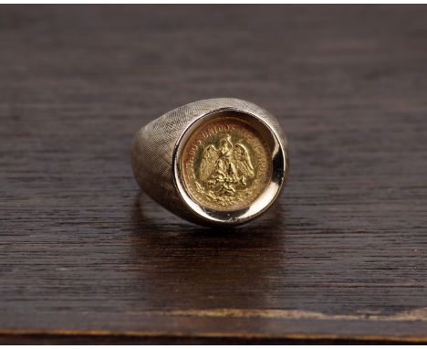 A Gentleman's 14k gold signet ring with textured shoulders and set with a mexican Two pesos gold coin. 13g Size O. 