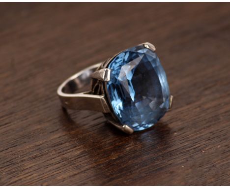 An Topaz and white metal dress ring. Single free cut Aquamarine 21mm x 19mm. in an open work white metal setting. 13.8g Size 