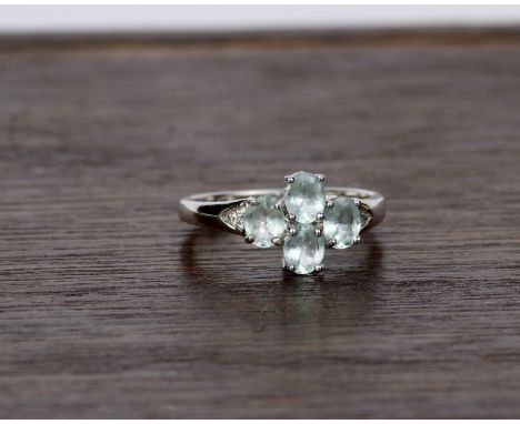 An 18k white gold and aquamarine dress ring. Set with four oval free cut aquamarines. Size N 4.4g 