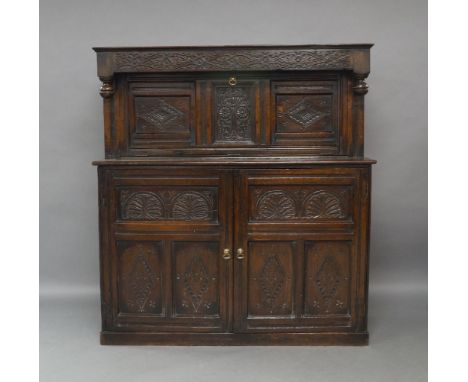 An oak court cupboard, 18th century and later, the carved frieze above carved fall front enclosing later drinks cabinet with 