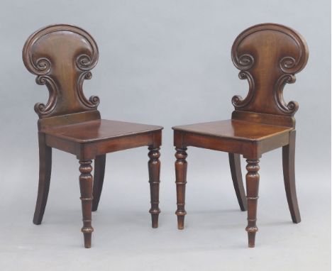 A pair of Victorian mahogany hall chairs, the carved back with scrolling design, raised on ring turned legs, 84cm high (2)bot