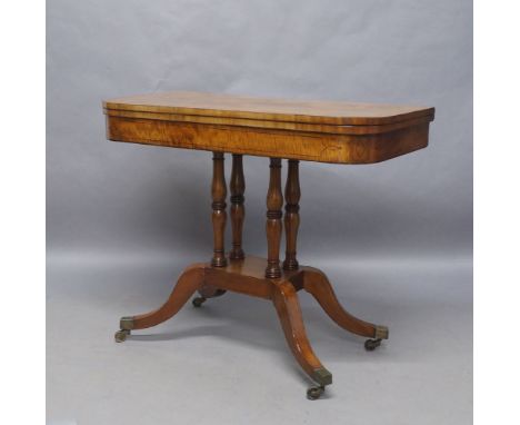 A Regency mahogany card table, ebony strung, the rectangular top with rounded edges, raised on ring turned baluster supports,