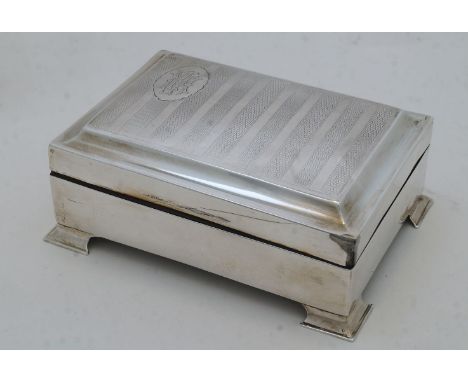 A silver cigarette box, marks rubbed, with striped engine turned cover having cartouche with monogram, wood lined, on bracket