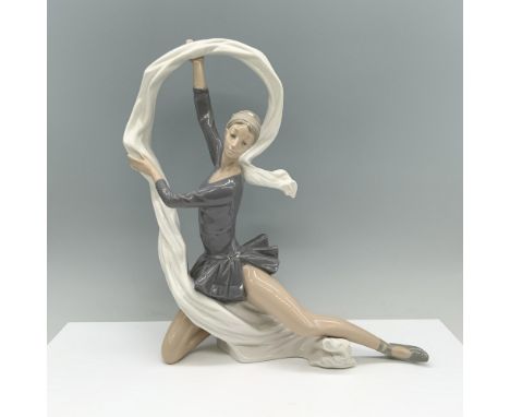 A ballet dancer in a stretched position holds a flowing veil above her head in grace. Nao by Lladro backstamp. Dimensions: 12