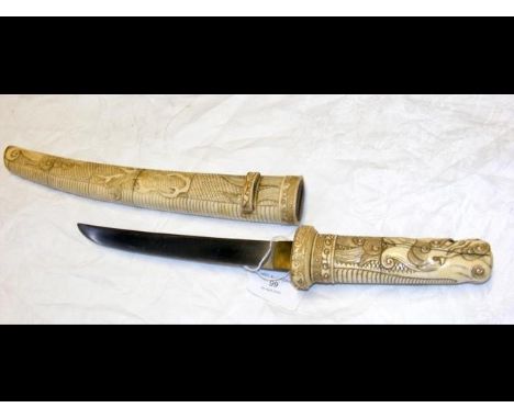 An antique Japanese 44cm long dagger with carved ivory handle and scabbard, the grip stylised in dragon with glass eyes